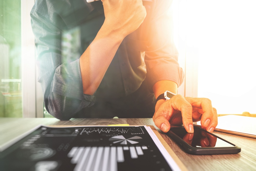 businessman working with digital tablet computer and smart phone with digital business strategy layer effect on wooden desk as concept